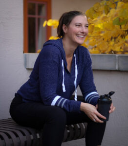 Kate sitting on a bench with waterbottle after workout.